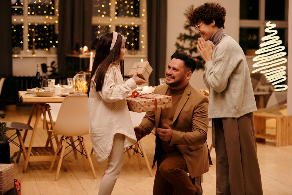 A joyful family exchanging gifts indoors during the Christmas season, capturing a moment of togetherness.
